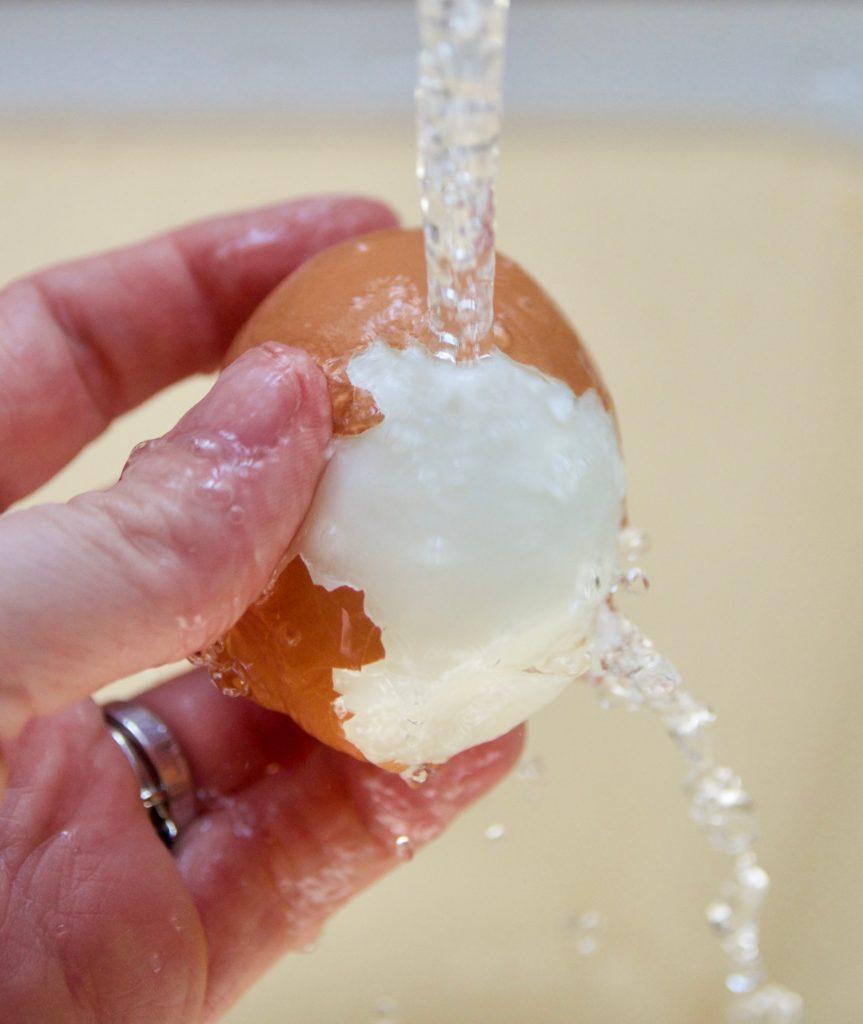 Rinsing the hard boiled egg under running water makes peeling the shell easier. 