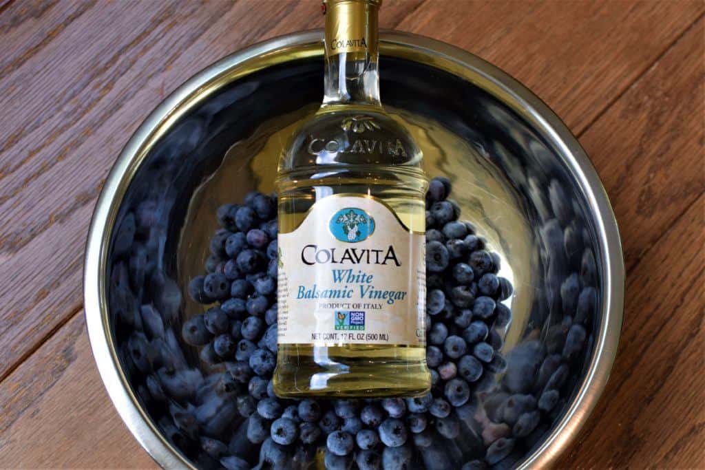 Bottle of vinegar over a bowl of blueberries