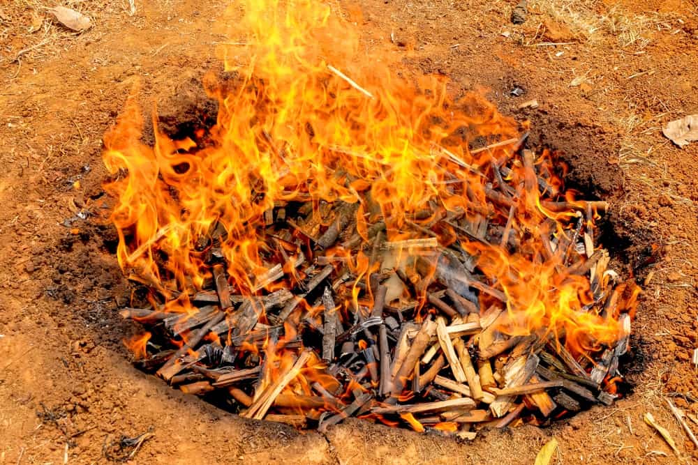 Burning wood in a pit to make biochar