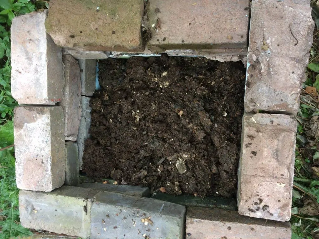 A heap of compost has been added to a newly constructed hotbed.