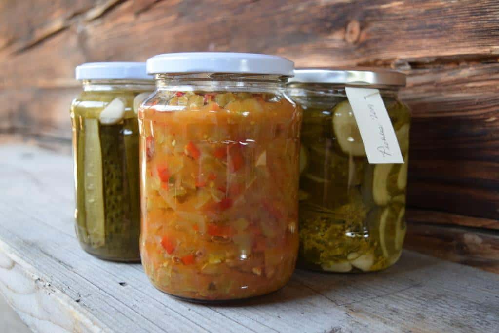 Several jars of homemade pickles sit on a weathered board.