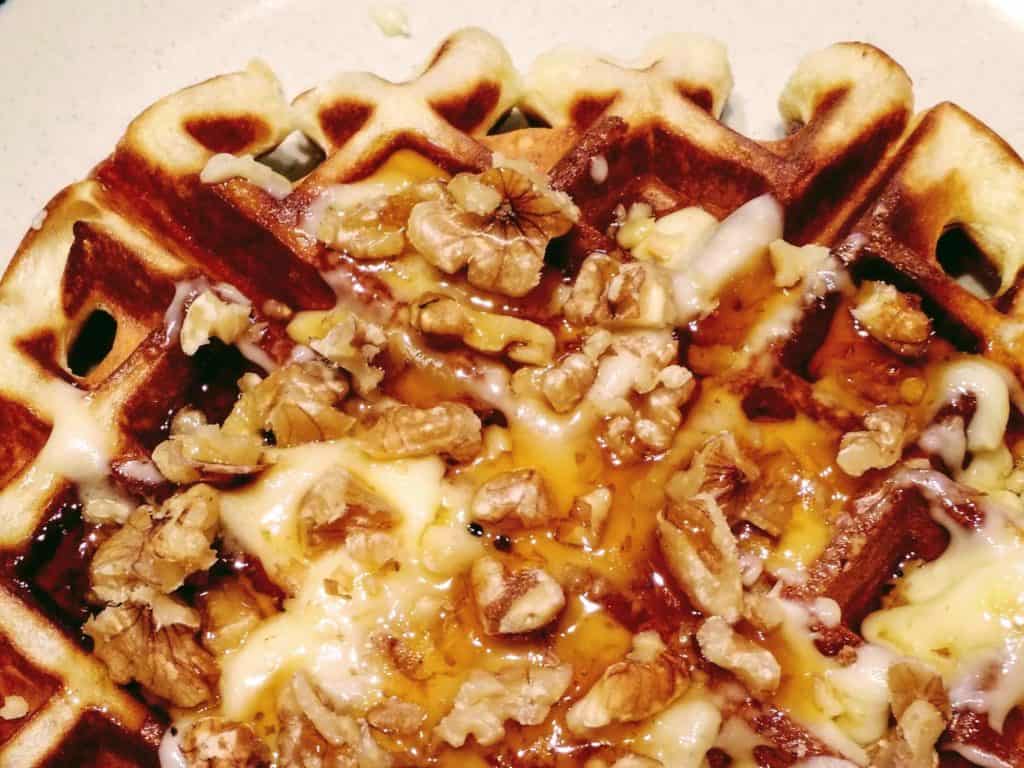 A pumpkin waffle topped with brie, walnuts and syrup.