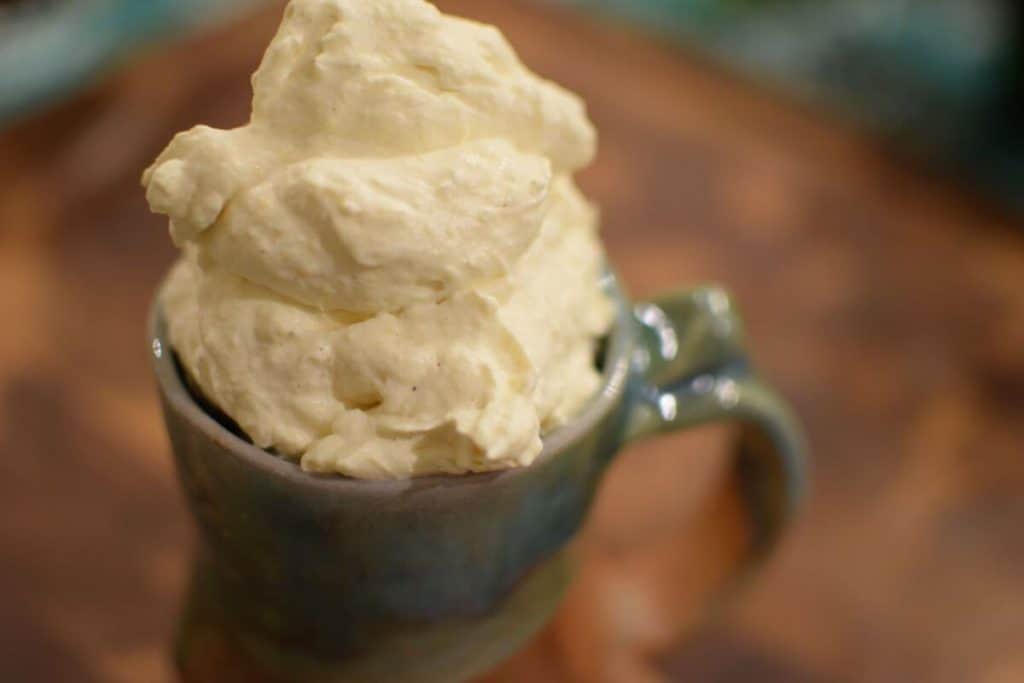 A mug of hot cocoa is topped with whipped cream.