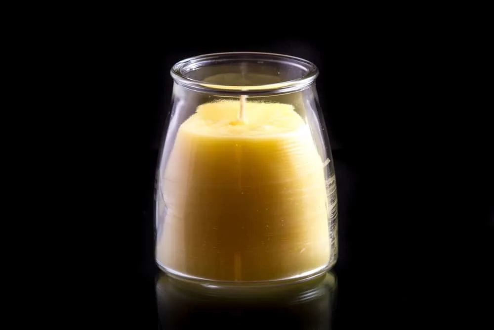A handmade beeswax candle in a glass jar