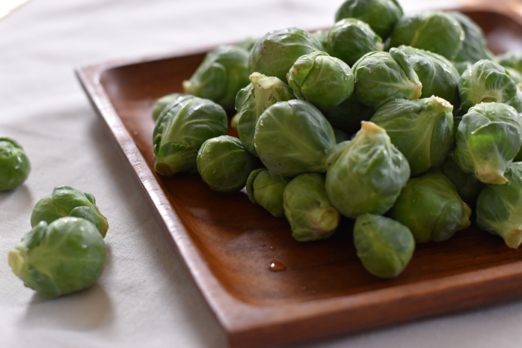 Teak dish with freshly washed Brussels sprouts.