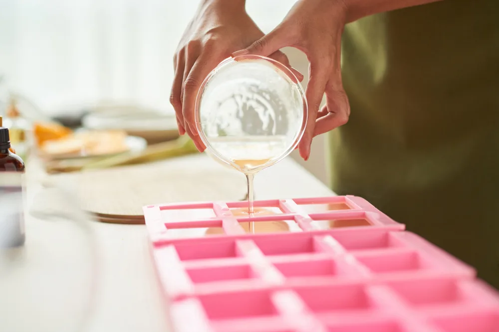 Pouring melted soap base into silicone molds