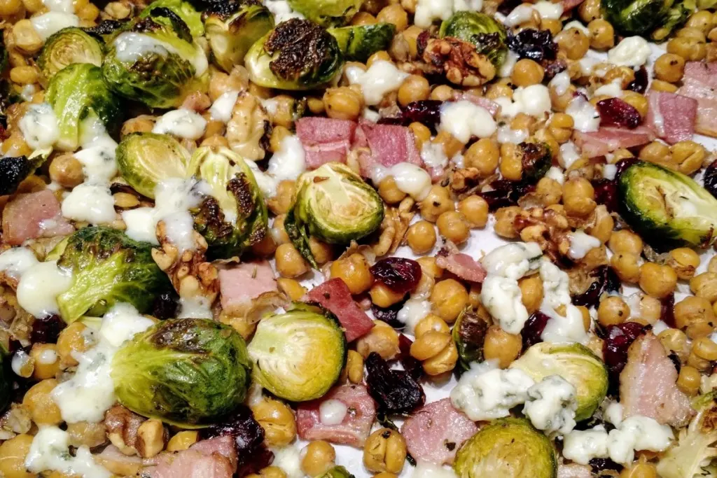 Close up of roasted Brussels sprouts with bacon, chick peas, Craisins and blue cheese.