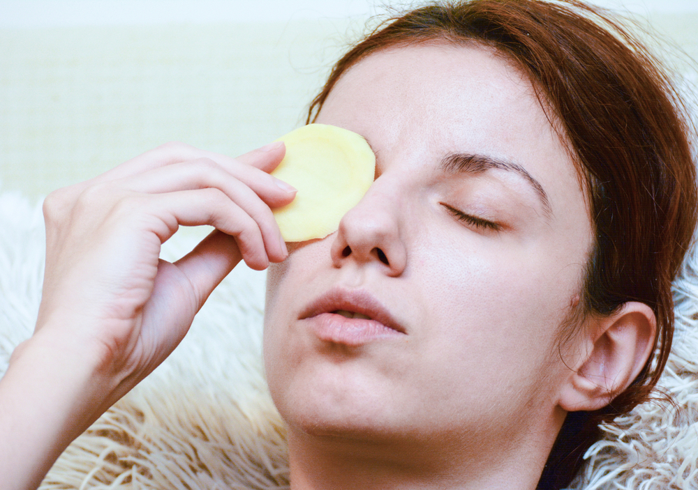 Woman putting potato slice on eyes