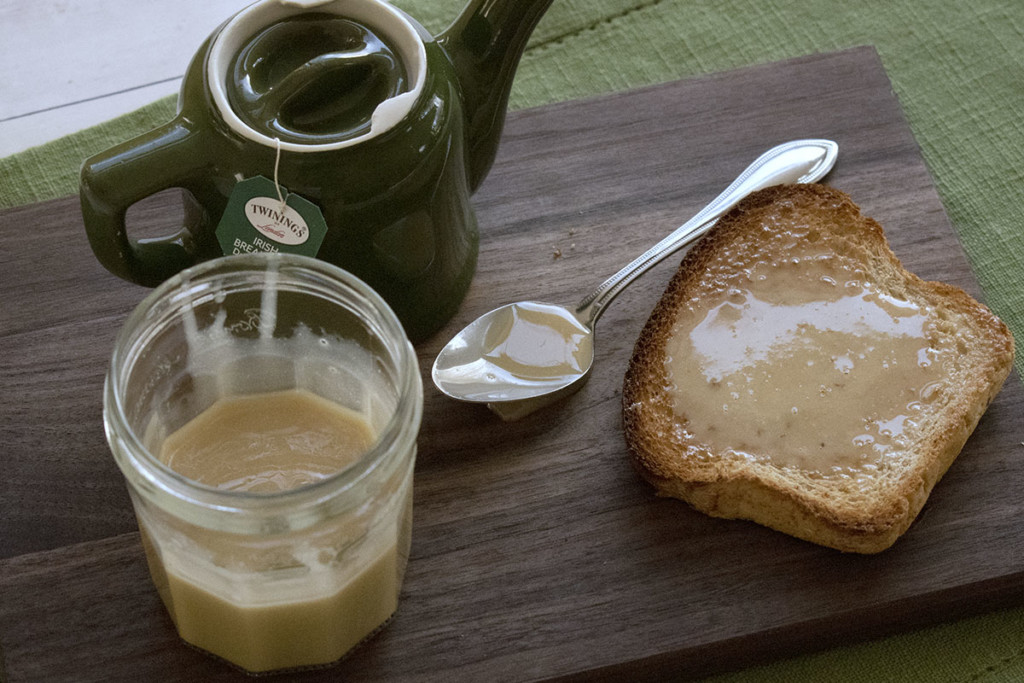 Tea set up on a cutting board with a slab of toast covered in maple cream.