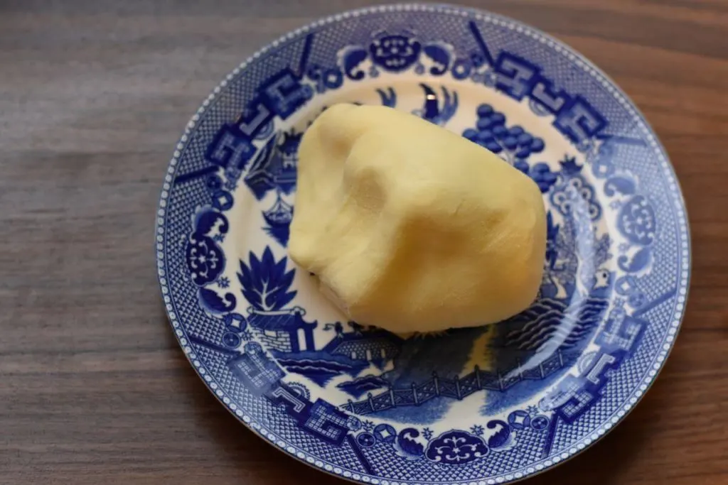 A lump of homemade butter is set out on a blue willow plate.