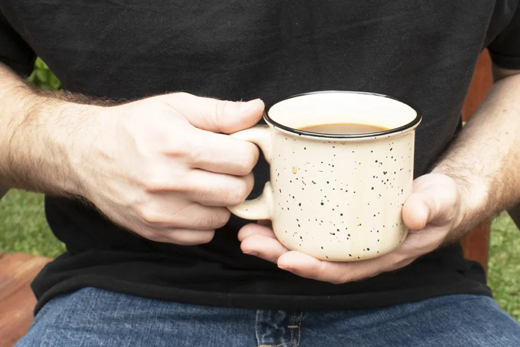 A man's hands holds a mug of coffee.