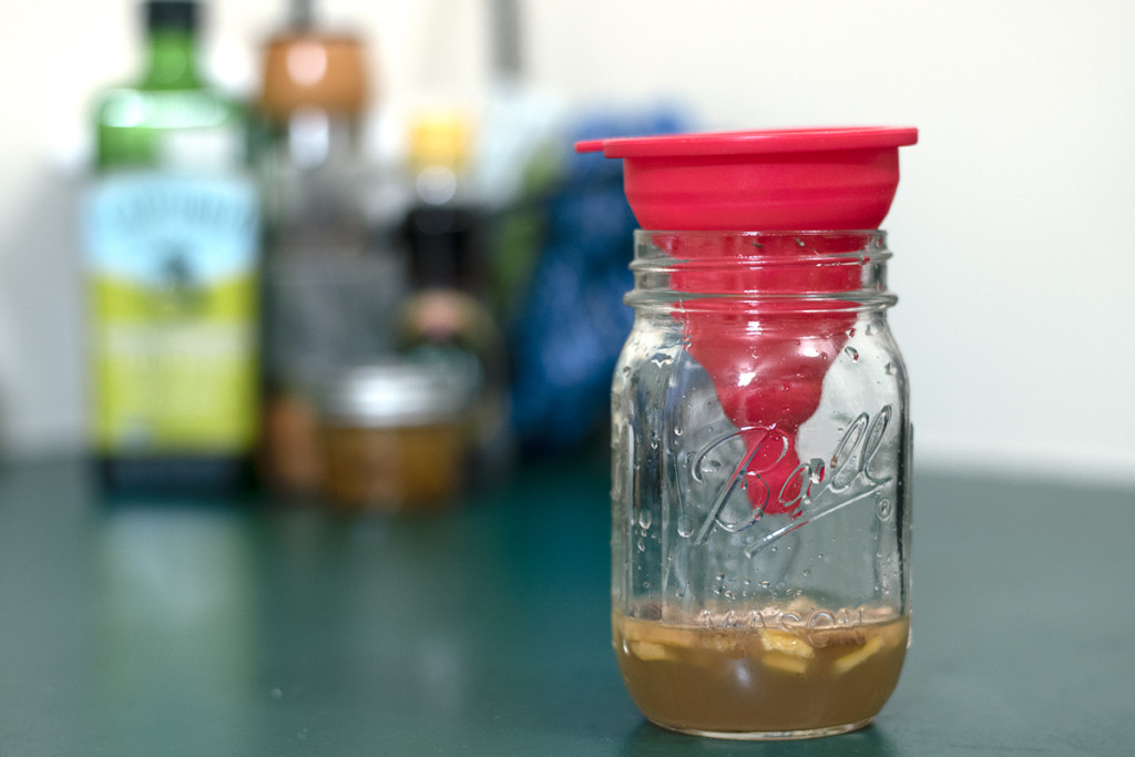 A jar is filled a quarter of the way with apple cider vinegar and chopped banana peels with a funnel in the mouth of the jar to catch flies.
