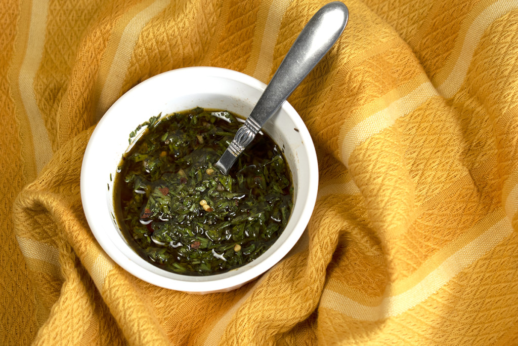 A small dish of chimichurri sauce with a spoon. 