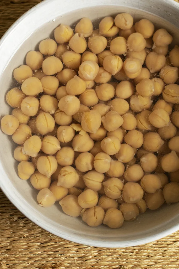 Bowl of chickpeas submerged in water.