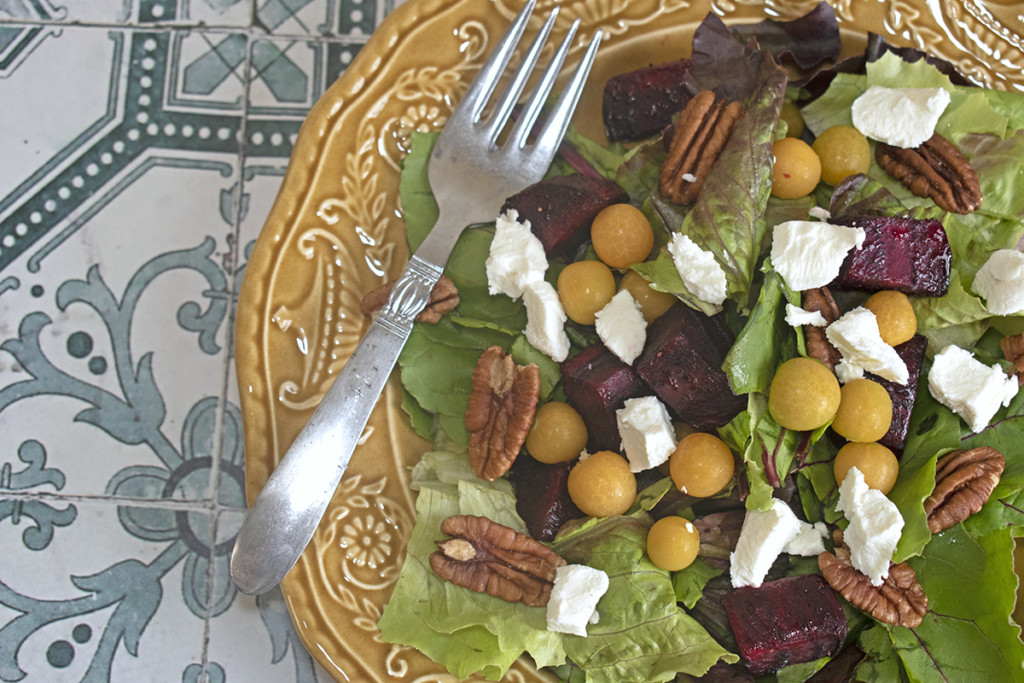 A salad of beet greens, roasted beets, ground cherries, and goat cheese