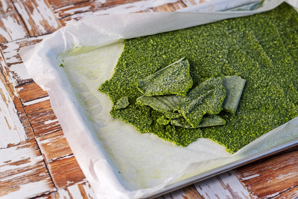 Frozen pesto basil, broken into slabs on a parchment-lined baking sheet. 