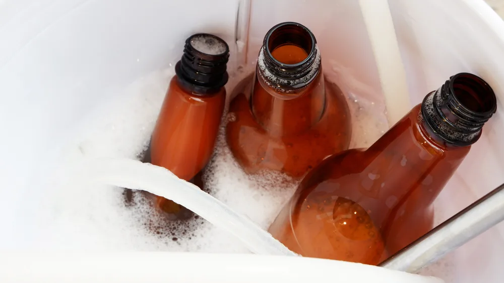 Empty beer bottles, tubing and other brewing equipment soak in a sanitizing solution.