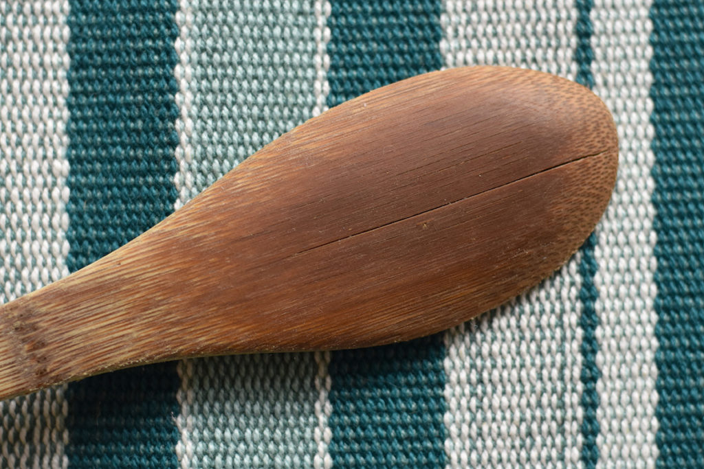 A wooden spoon with a long crack in it.