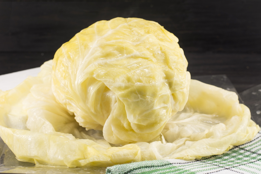 A whole fermented head of cabbage laying on a cutting board.