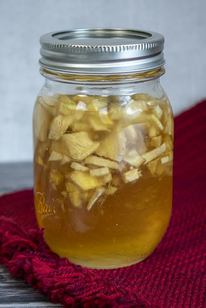 A jar of honey mixed with fresh ginger is sealed in preparation to make honey-fermented ginger.