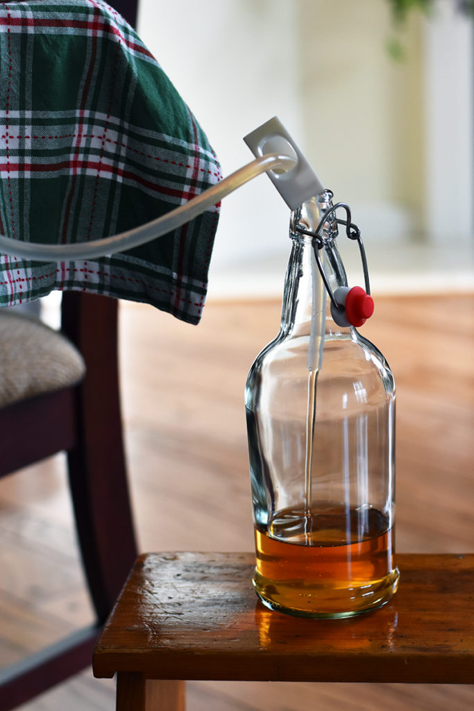A swing-top bottle is being filled with spiced pumpkin cider.