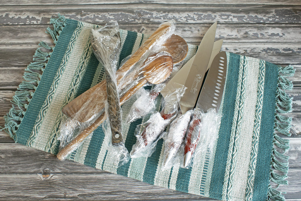Several kitchen knives and tools are shown wrapped in plastic wrap.
