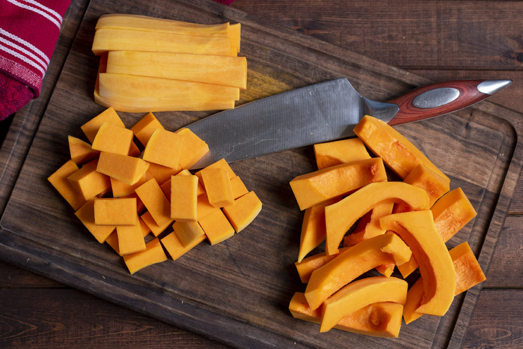 A butternut squash has been sliced into various sized strips and cubes.