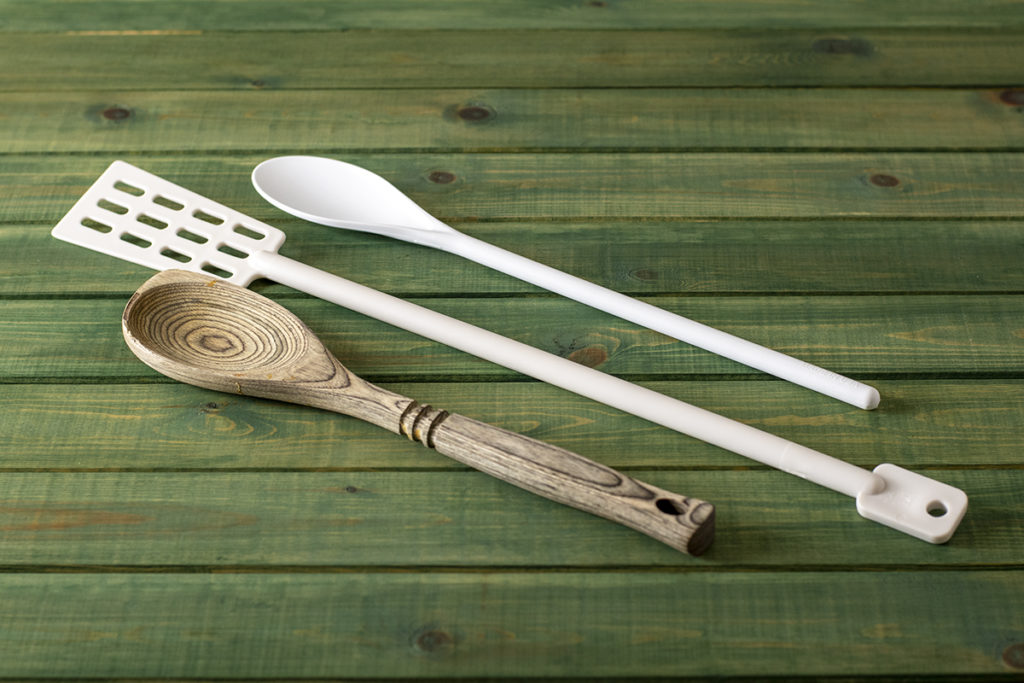 A long-handled plastic spoon, a brew paddle, and a wooden spoon.