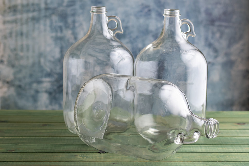 Three one-gallon glass jugs, one is lying on its side.