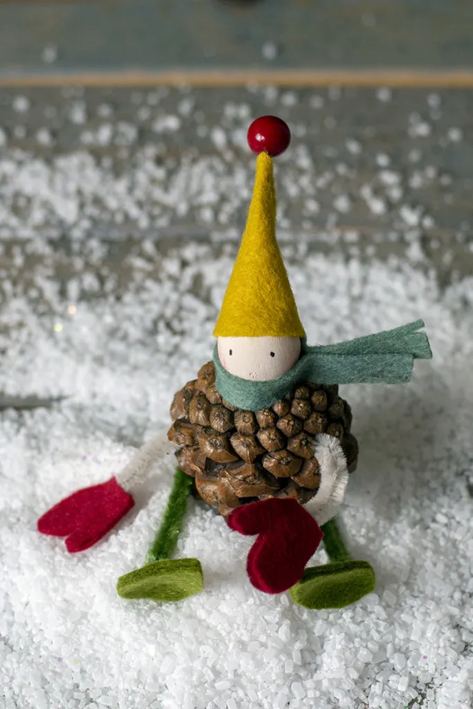A small elf made from a pine cone and pieces of felt and pipe cleaners. 