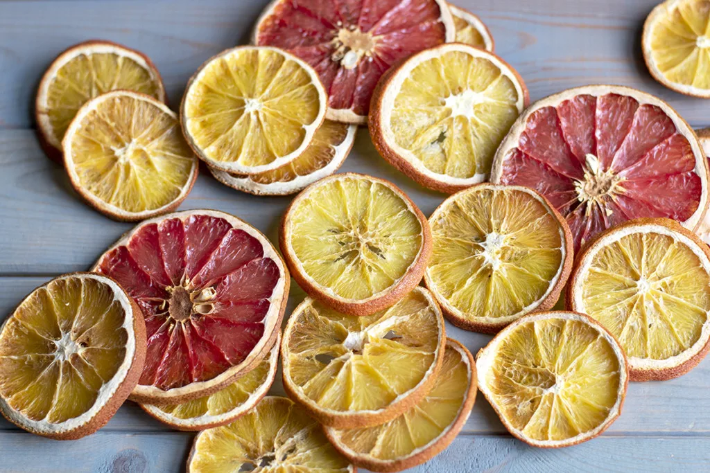 Several citrus slices are spread out on a wooden background. 