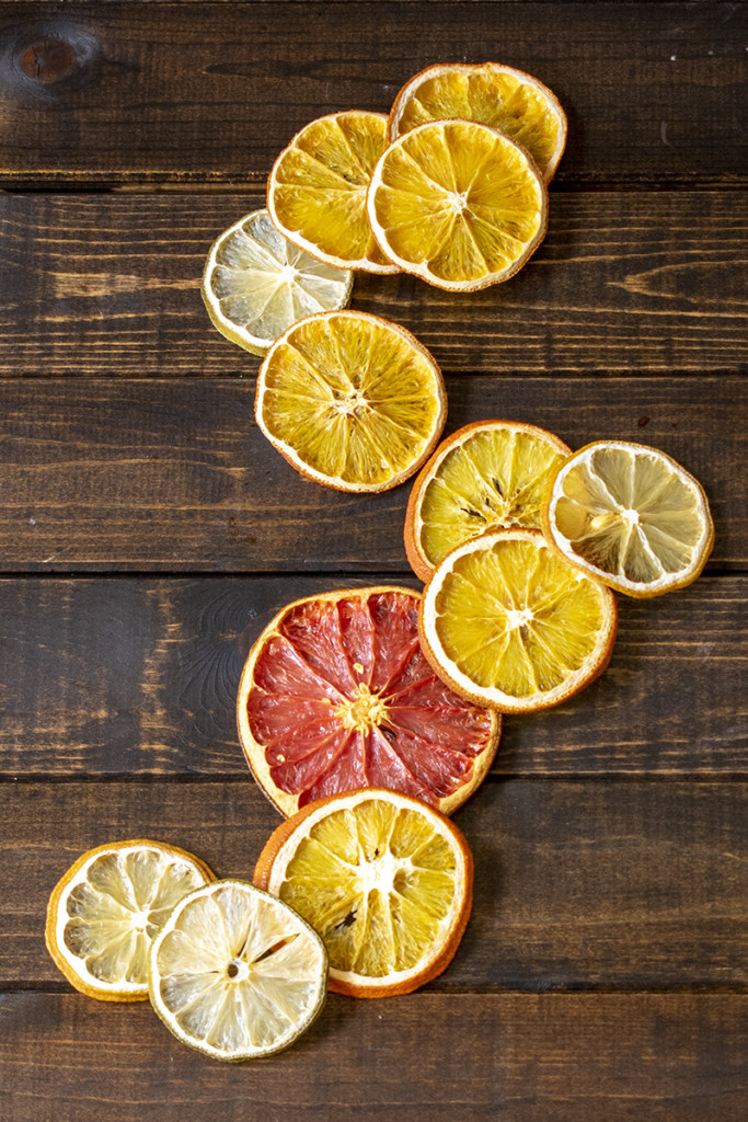 Several dried citrus fruit slices scattered on a wooden background