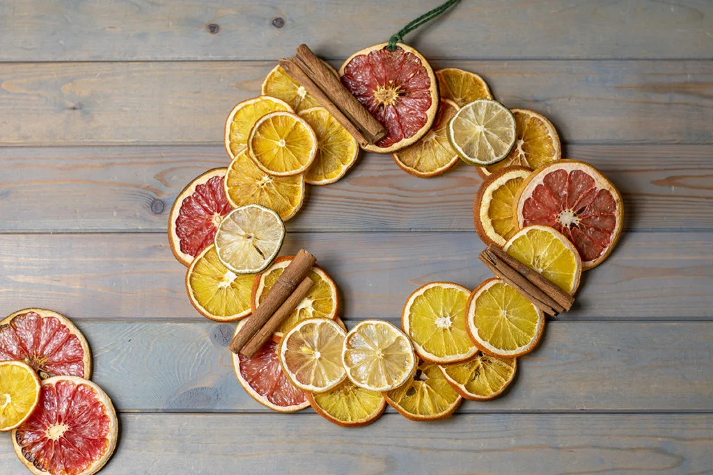 A wreath made out of dried citrus slices with cinnamon stick accents.