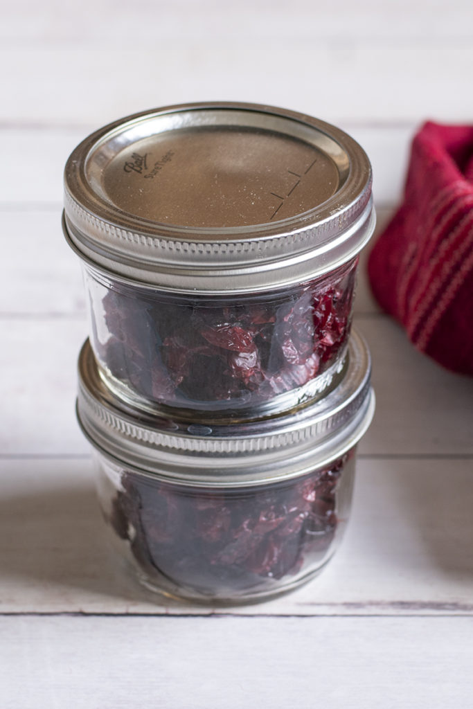 Two small jars filled with dried cranberries, one stacked on top of the other.