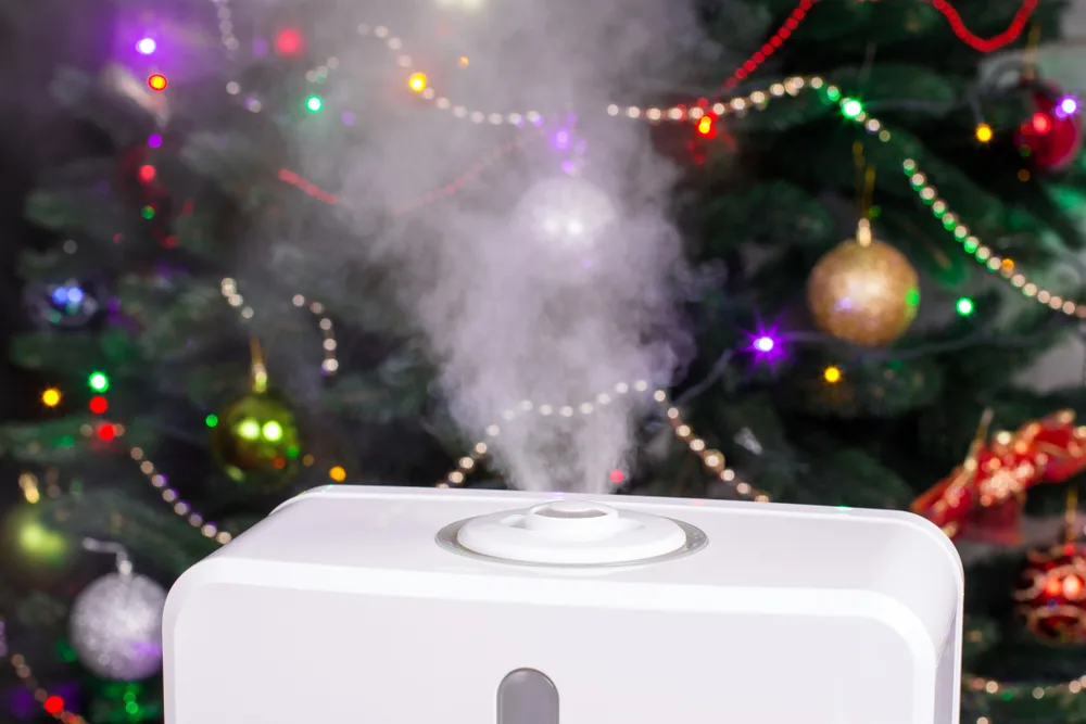 A cold mist vaporizer running in front of a Christmas tree.