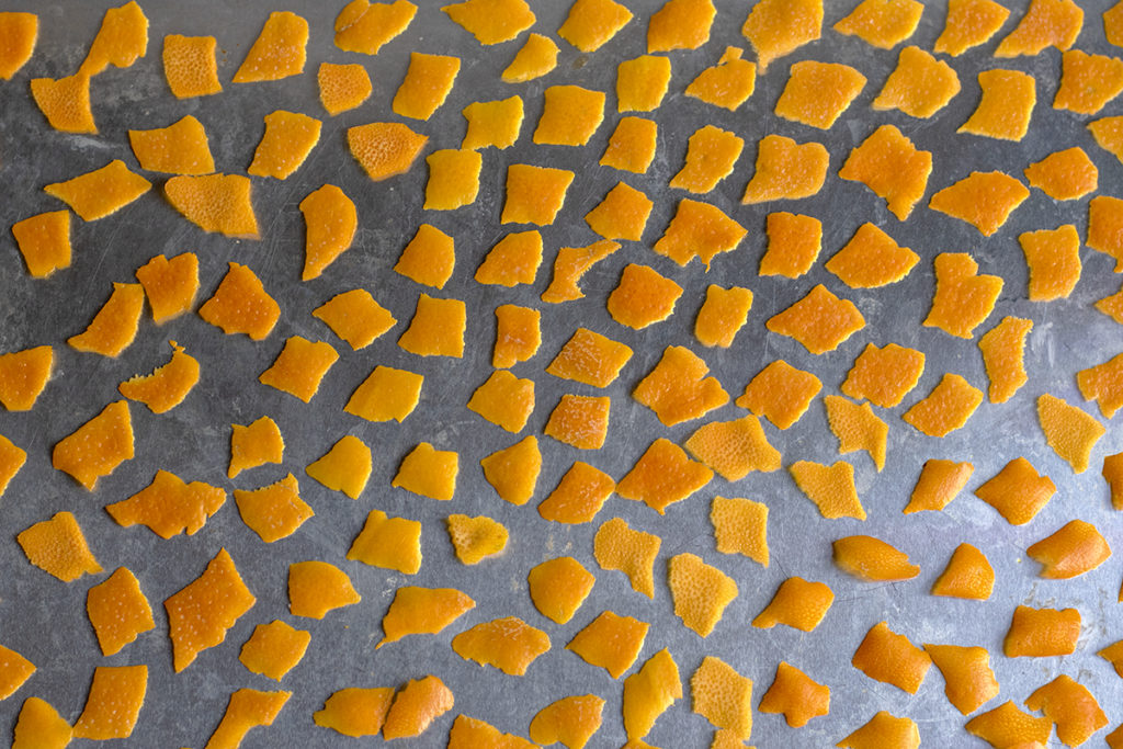 Small pieces of orange peel arranged on an aluminum baking sheet.