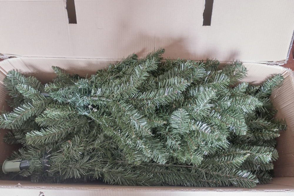 An artificial Christmas tree in pieces packed in a cardboard box.
