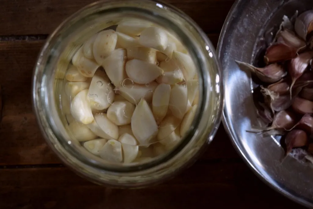 Overhead view of lacto-fermented garlic in a jar. 
