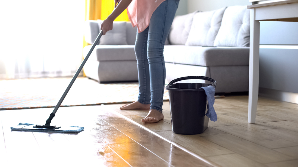 A woman is mopping her living room floor.