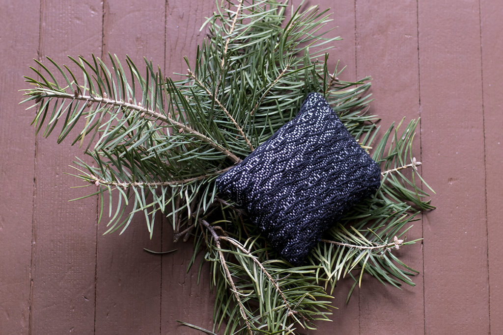 A balsam pine sachet rests on a few small pine branches.