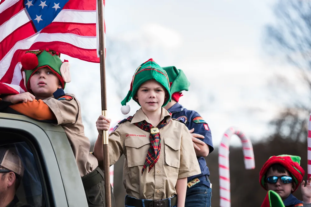 Several boy scouts are dressed up wearing elf hats for Christmas.