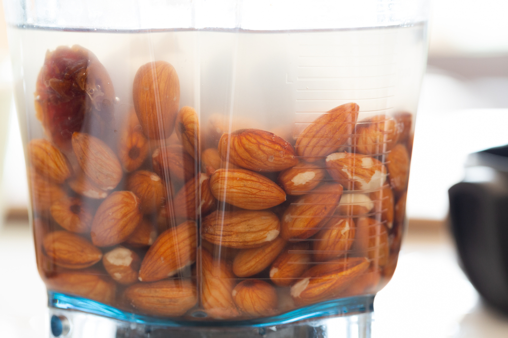 Almonds soaking in water in a blender jar.