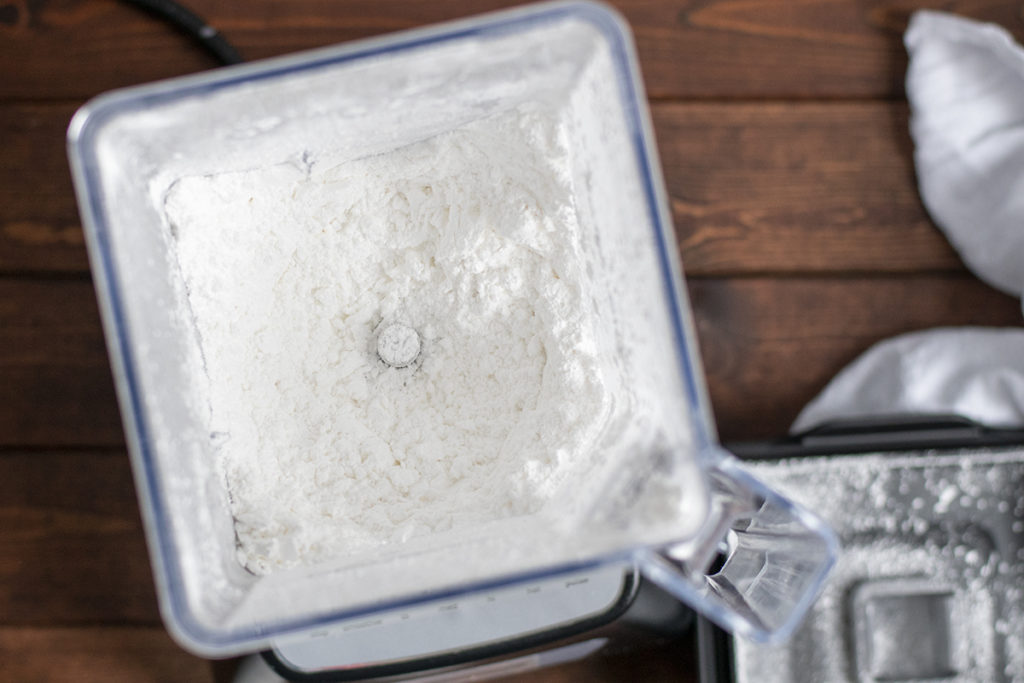 Close up of a blender jar full of powdered sugar.