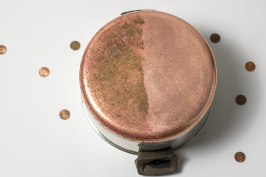A copper-bottomed pan is shown with half of it shiny and clean after it was polished with ketchup.