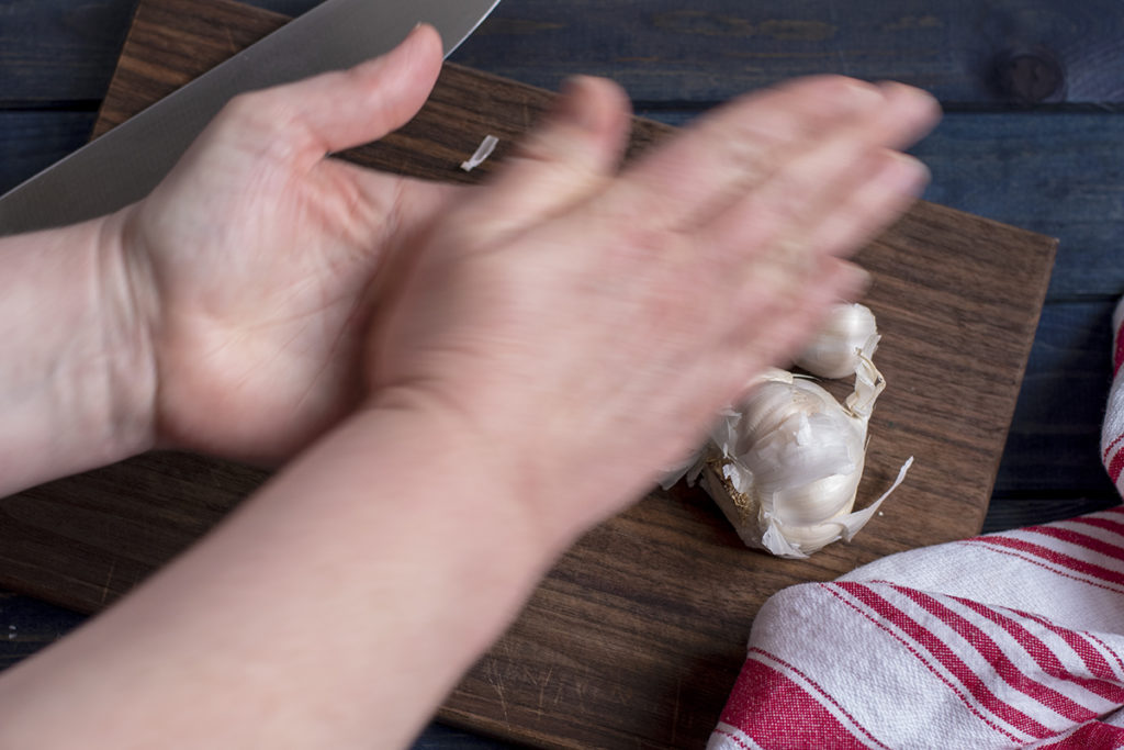 I am rubbing a garlic clove between my hands to peel it. My hands are blurry in the photo.