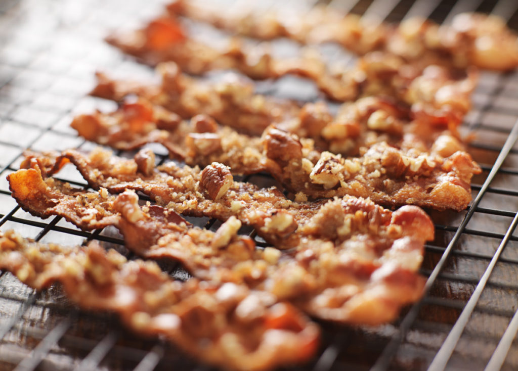 Slices of candied bacon cool on a rack.