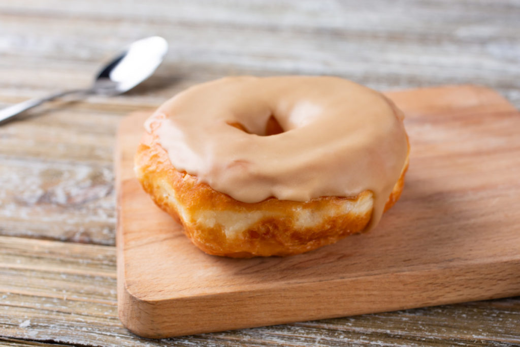 A donut is glazed with maple syrup.