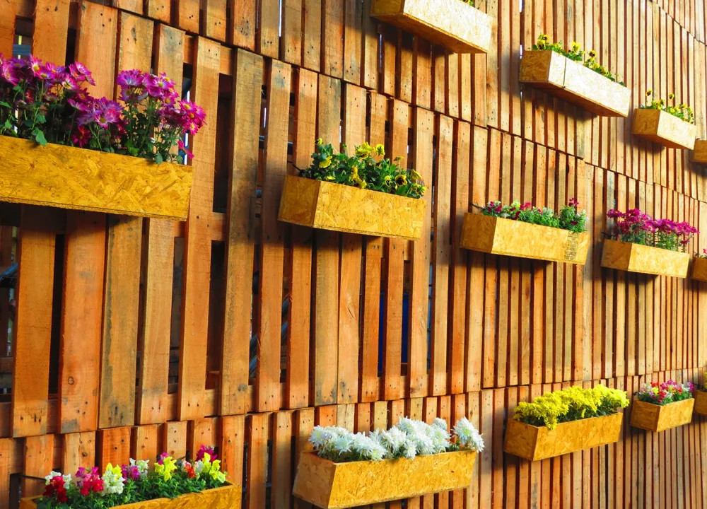 Pallet fence hung with flower planters made of pallet pieces.