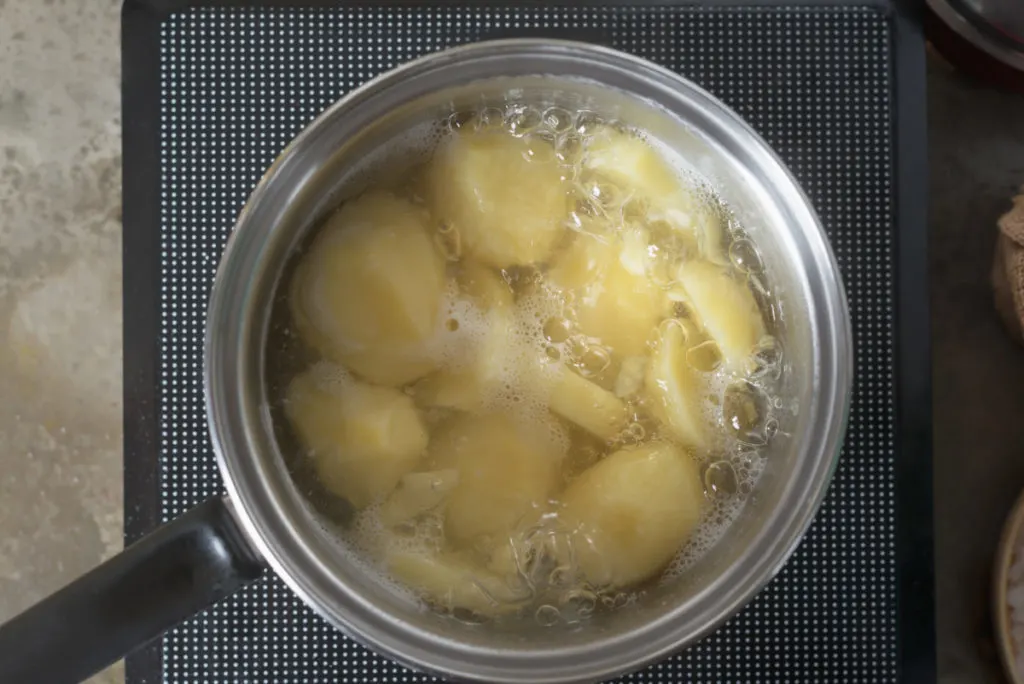 A pot of boiling potatoes on a convection plate.