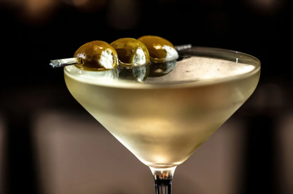 A dirty martini with blue cheese stuffed olives as a garnish.